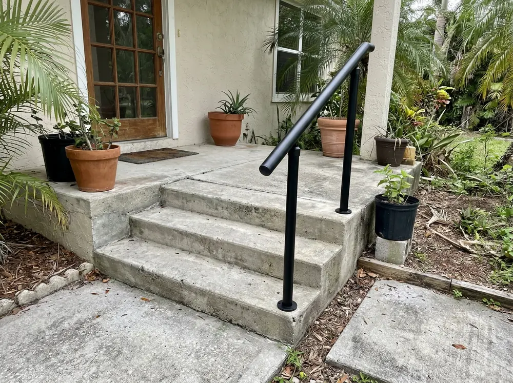 Round black aluminum handrail on posts beside concrete entry steps