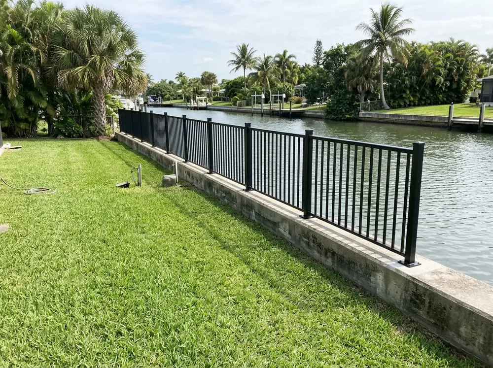 Low aluminum picket railing along a concrete seawall cap at the back of a waterfront yard